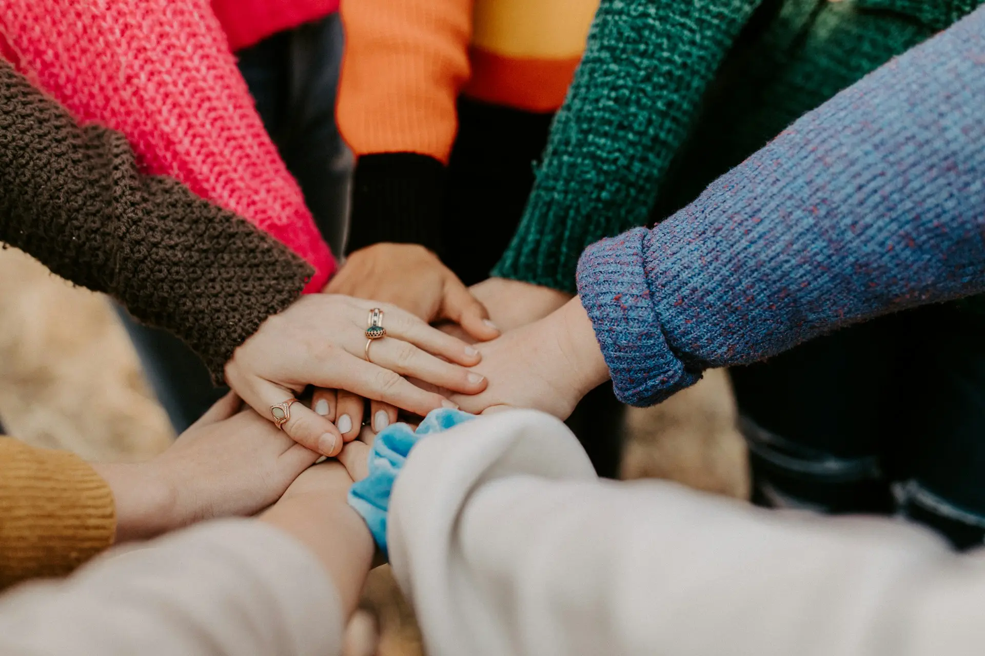Hände mehrerer Menschen übereinander als Symbol für Zusammenhalt, Vielfalt und Zusammenarbeit